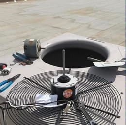 911 Air Repair technician replacing the condenser fan motor on a rooftop AC unit